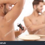 stock-photo-handsome-young-man-applying-deodorant-in-bathroom-space-for-text-1255641058